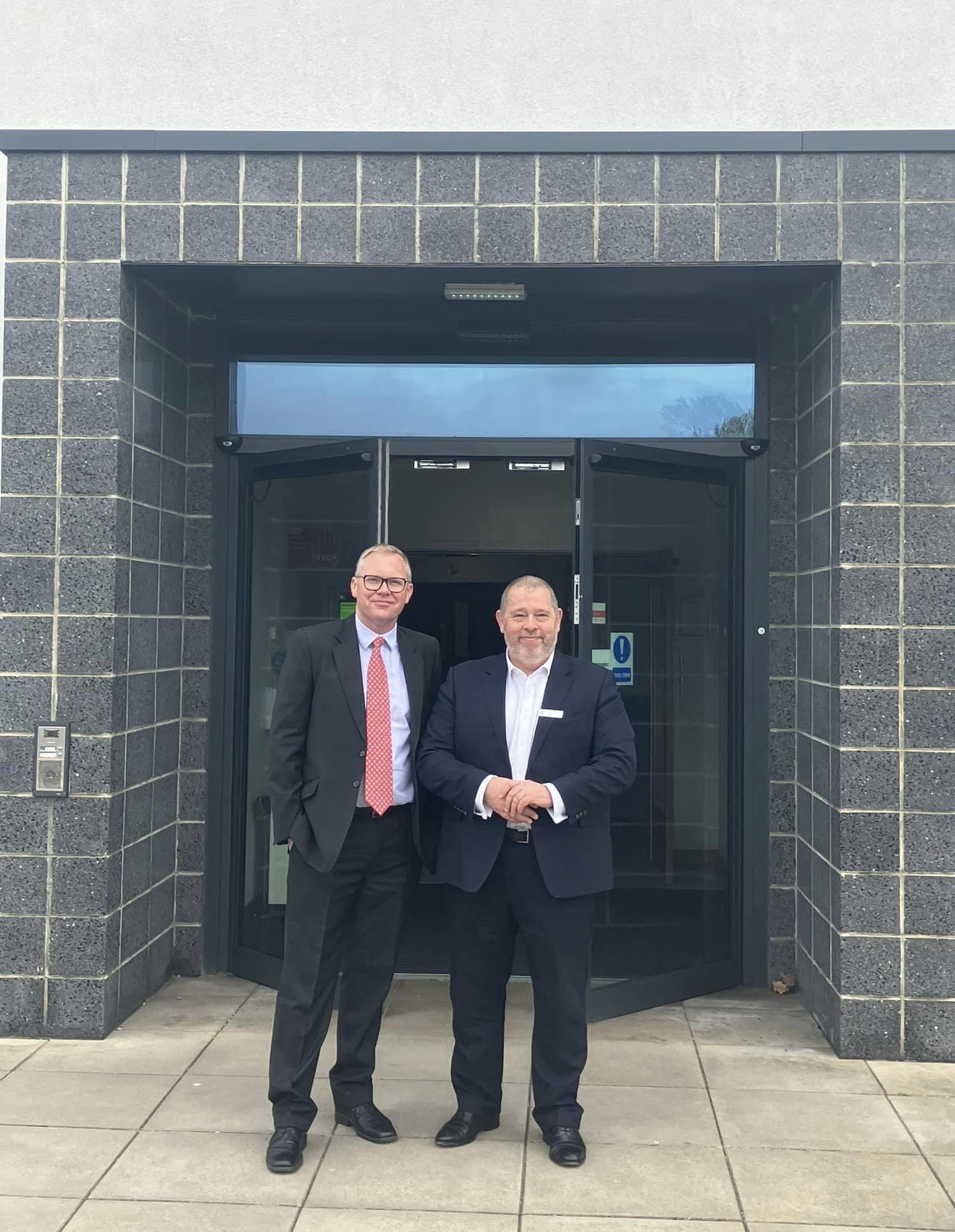 two men in suits stood together smiling